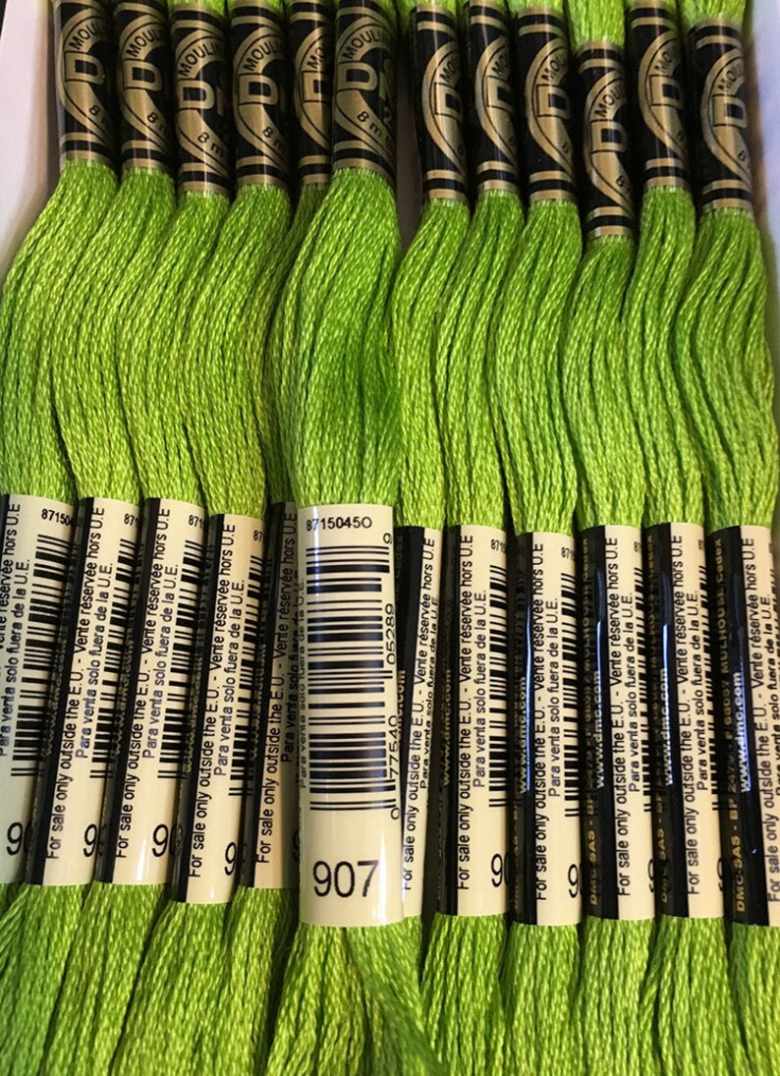 Multiple skeins of 907 Light Parrot Green DMC embroidery floss.