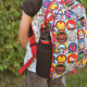 A child wearing a multi-colour backpack with a water bottle in the side pocket.