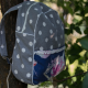 A blue and white backpack hanging in a tree.