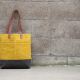 Mustard color wool and wax tote against a concrete wall