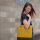 Mustard color wool and wax tote on Anna's right shoulder
