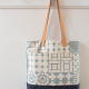 Light blue stamped wool and wax tote hanging on wall peg