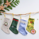 Four miniature Christmas stocking hanging from a branch against a white background.