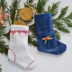 Two miniature Christmas stockings - one blue, one white - laying on a cedar branch. One has two chocolate coins coming out of the top of the stocking.