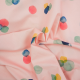 Pink fabric with multicolored, organically shaped dots, fabric has been twisted at the center