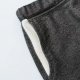 Pocket details of a pair of grey shorts  laying on a white surface.