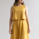 A woman of medium height and build wears a yellow knit dress with full A-line skirt and flowy  bodice overlay