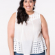 A woman models a white, paneled sleeveless top with eyelet yoke and gathered eyelet panels at the hem on either side.