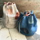 Two round drawstring bags, one mostly cream and pink, the other shades of blue, sitting on a wooden surface.