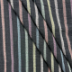 Photo of black fabric with muted rainbow stripes. Fabric is folded in several diagonal pleats to show texture