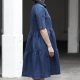 Side-view photo of woman wearing Avery, a shirtdress with a two-tiered gathered skirt, in dark blue.