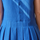 Close-up back-view photo of woman wearing Harper, showing button-down back bodice and box-pleated skirt, in blue.