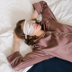 Photo of woman lying in bed with a sleep mask over her eyes.