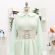 Front-view photo of Kiri, an oversized button-down shirtdress with a large peter pan collar and pleated trim at the bottom of the sleeve cuffs and around the collar, in mint green, cinched at the waist with Mood's Adonis Corset Belt, on a dress form.